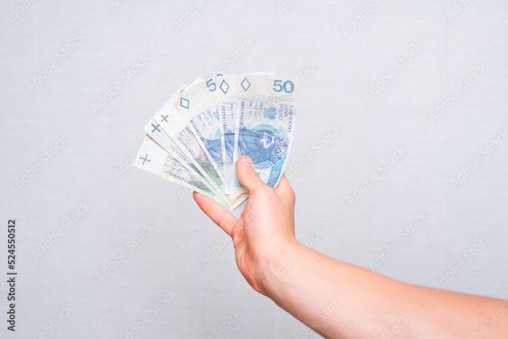 close-up of 100 and 50 zloty banknotes held in the hand on a light background - obrazy, fototapety, plakaty 
