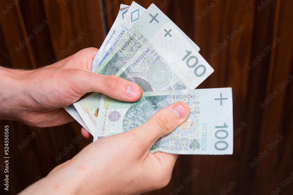 The man holds Polish zlotys in banknotes. Concept showing polish economy, finance and policy. Rising inflation in Poland. The man holds Polish zlotys in banknotes. Concept showing polish economy, finance and policy. Rising inflation in Poland.