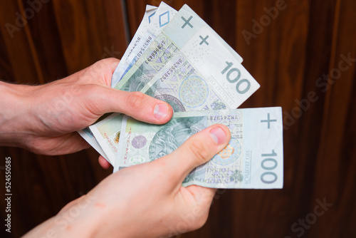 The man holds Polish zlotys in banknotes. Concept showing polish economy, finance and policy. Rising inflation in Poland. 