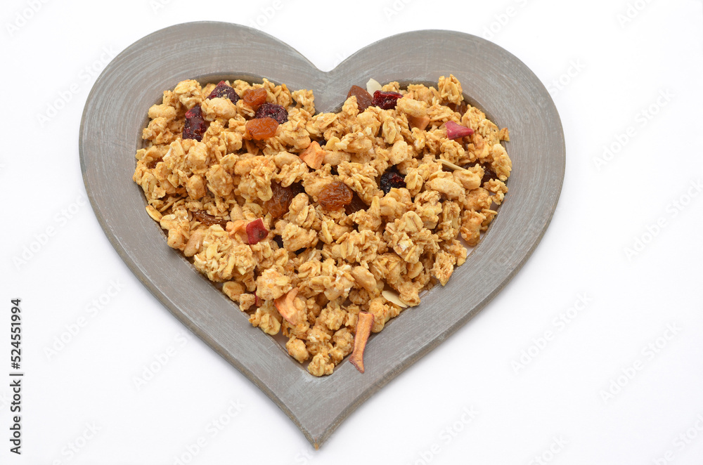 traditional organic muesli with dried fruits in a heart-shaped frame on a white background traditional organic muesli with dried fruits in a heart-shaped frame on a white background