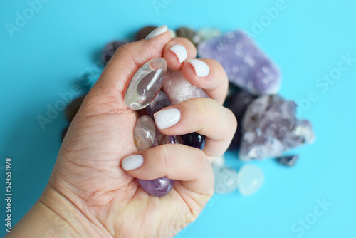 Beautiful purple amethyst crystals in rock crystal in hand. Semi-precious stones in a female hand against the background of other precious stones. Selective focus.