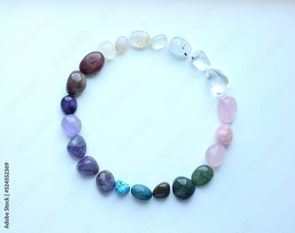 The circle is lined with natural minerals. Semi-precious stones of different colors are processed. Amethyst, rose quartz, rock crystal and apatite. Frame of precious stones on a white background. The circle is lined with natural minerals. Semi-precious stones of different colors are processed. Amethyst, rose quartz, rock crystal and apatite. Frame of precious stones on a white background.