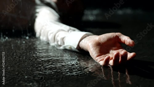 dead man in puddle in rain in night, closeup view of hand, crime scene, flashes of camera of police
