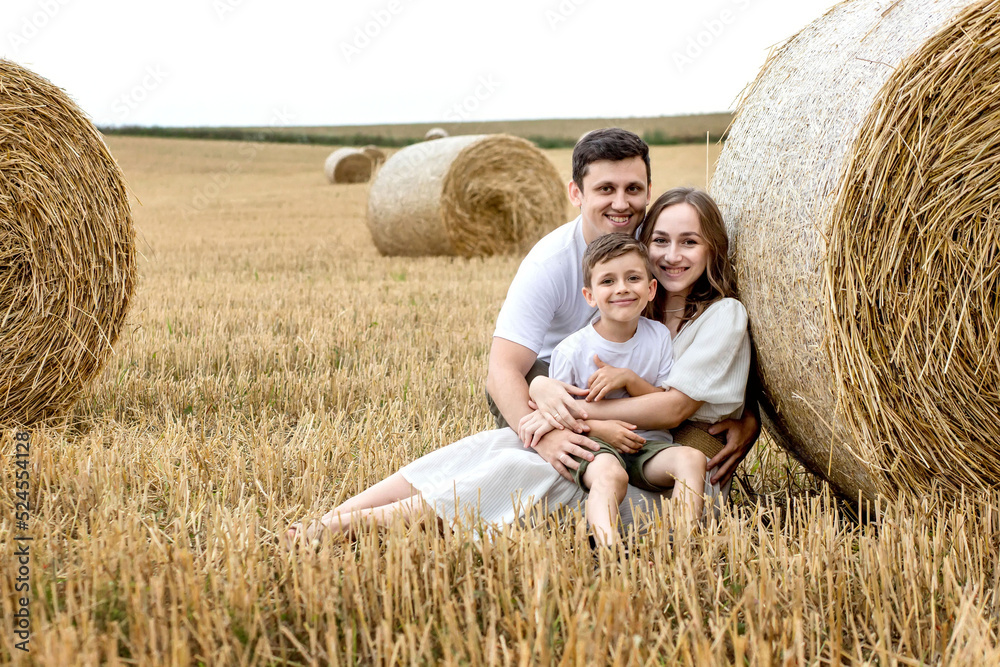 Young family mom dad and son on the field near the straw bales. Family photo session Young family mom dad and son on the field near the straw bales. Family photo session