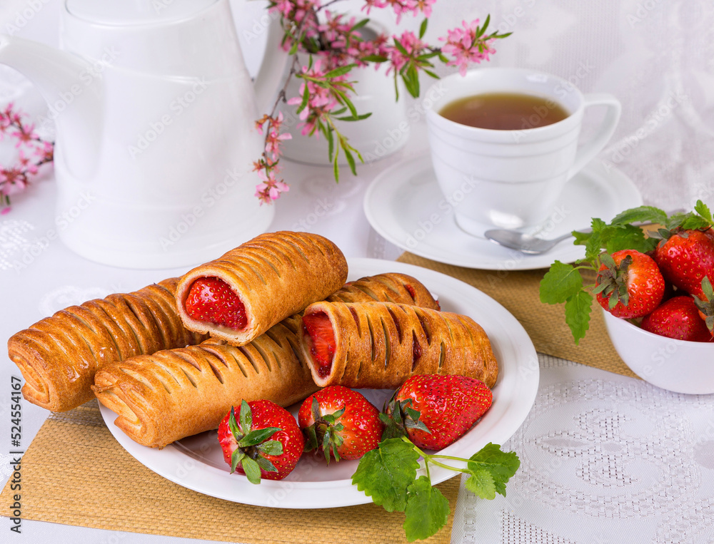 puff pastries stuffed with strawberries, on a white dish, with a cup of tea, on a light background puff pastries stuffed with strawberries, on a white dish, with a cup of tea, on a light background