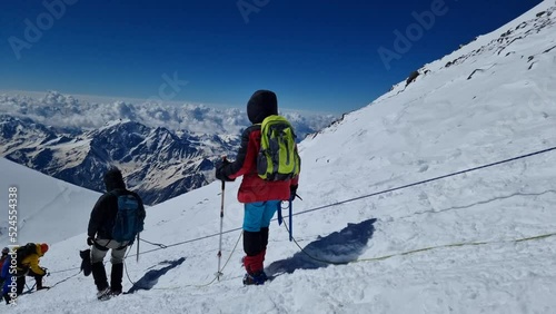 organized touristic group is overcoming mountain pass in Elbrus region, alpinists are walking photo