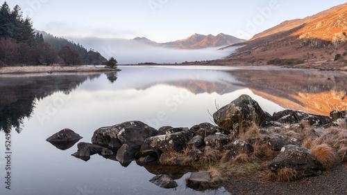 Canvas Print Mountain view with temperature inversion plus lake with reflections and rocks in