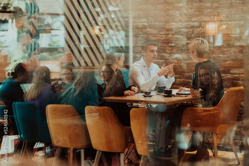 Happy businesspeople smiling cheerfully during a meeting in a coffee shop. Group of successful business professionals working as a team in a multicultural workplace.