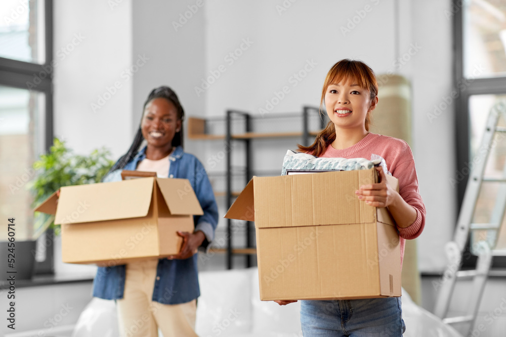 moving, people and real estate concept - happy smiling women with boxes at new home moving, people and real estate concept - happy smiling women with boxes at new home