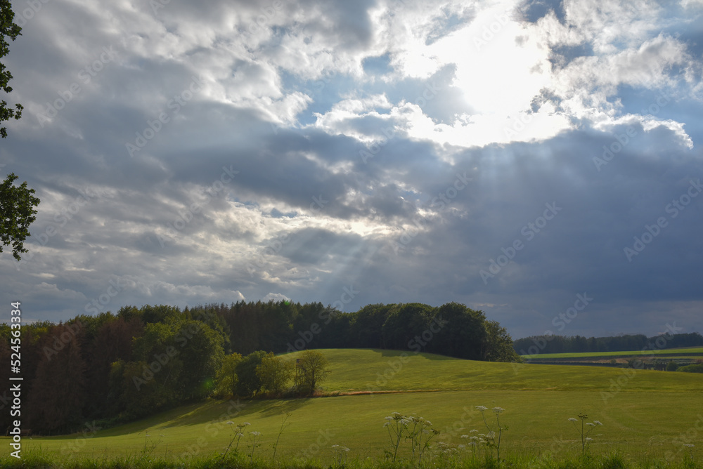 cloudy sky with sunbeams breaking through a field in germany