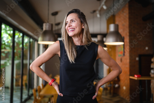 One woman middle age caucasian female standing at home in dining room or restaurant happy smile confident wear black waist up copy space front view portrait