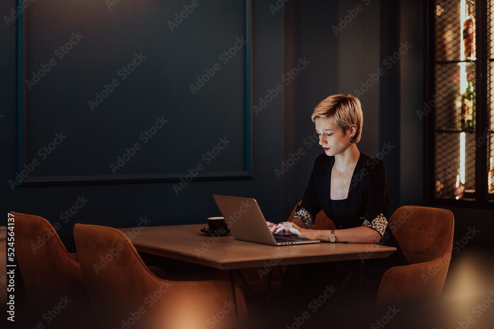Businesswoman sitting in a cafe while focused on working on a laptop and participating in an online meetings. Selective focus. High quality photo Businesswoman sitting in a cafe while focused on working on a laptop and participating in an online meetings. Selective focus. High quality photo
