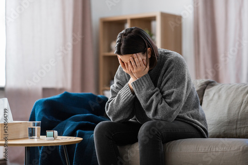 mental health, psychological problem and depression concept - stressed woman with sedative medicine or painkiller on table having headache at home