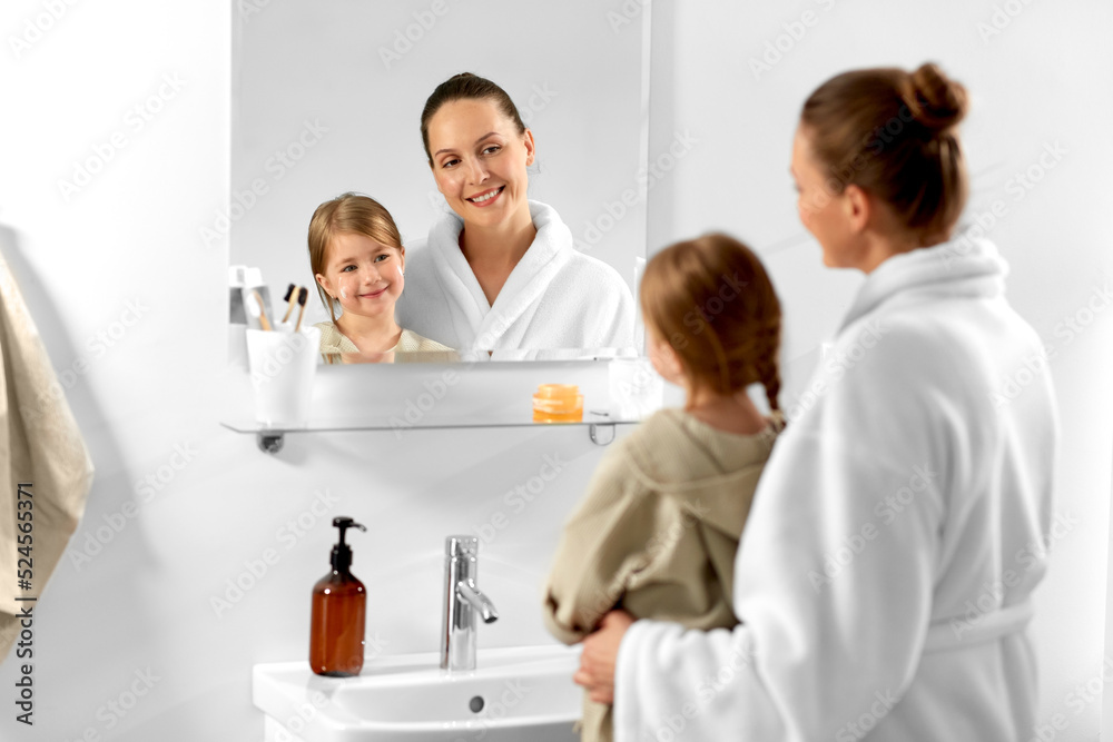 beauty, hygiene and people concept - happy smiling mother and daughter with moisturizer in bathroom beauty, hygiene and people concept - happy smiling mother and daughter with moisturizer in bathroom