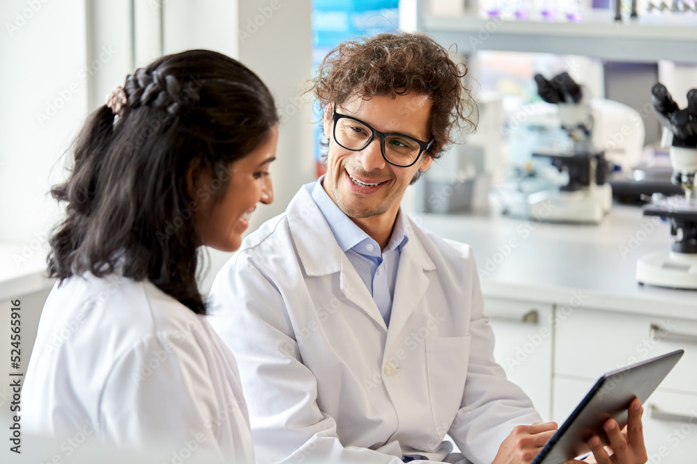 Obraz premium science research, work and people concept - happy international scientists with tablet pc computer working in laboratory