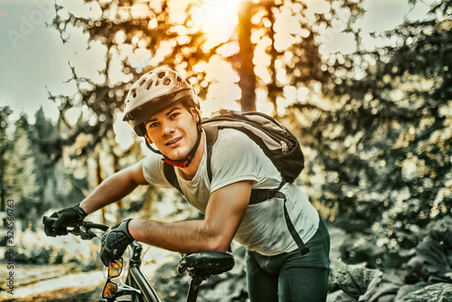 Tired bicyclist in sport clothes and helmet taking break after outdoors training. Healthy caucasian man spending free time for workout on fresh air.