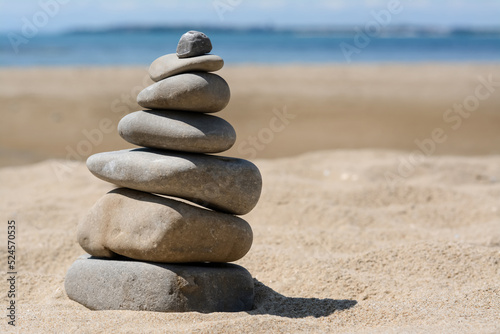 Stack of stones on beautiful sandy beach near sea  space for text