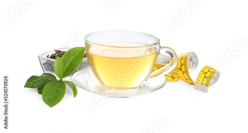 Glass cup of diet herbal tea, measuring tape, dry and fresh leaves on white background