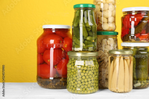 Obraz na plátně Jars of pickled vegetables on white wooden table