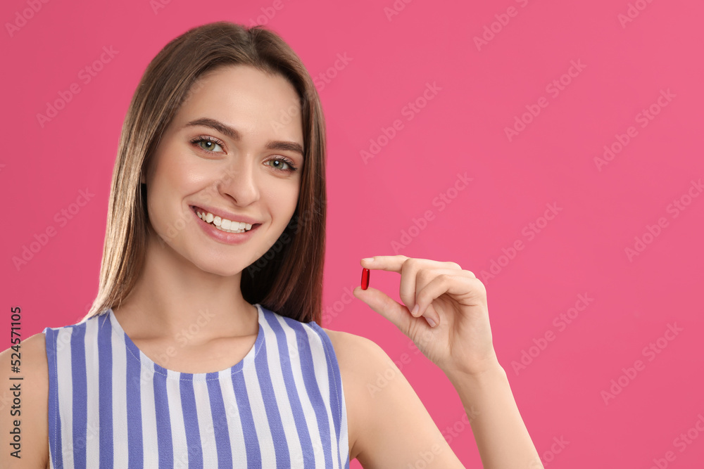 Young woman with vitamin pill on pink background Young woman with vitamin pill on pink background
