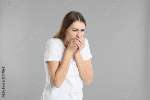Woman suffering from nausea on grey background. Food poisoning