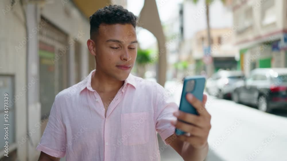 Young latin man smiling confident having video call at street