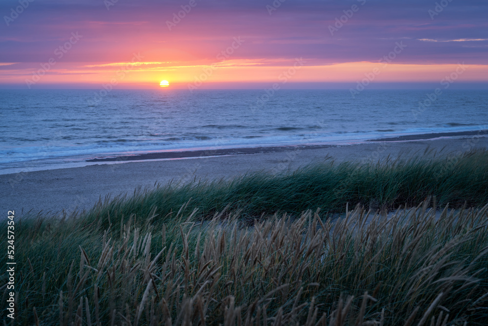 Sonnenuntergang über der Nordsee mit Strand und Düne im Vordergrund