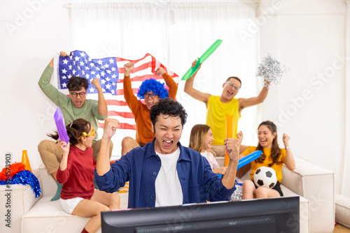 Group of Asian man and woman friends watching soccer games world cup competition on television with eating snack together at home. Sport fans people shouting and celebrating sport team victory match. photo