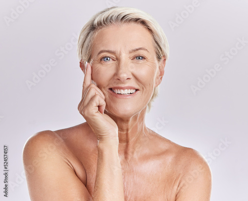 Senior woman applying beauty sunscreen  face cream or moisturizing lotion on skin isolated on studio background. Portrait skincare  health and wellness lady with wrinkles and anti aging moisturizer