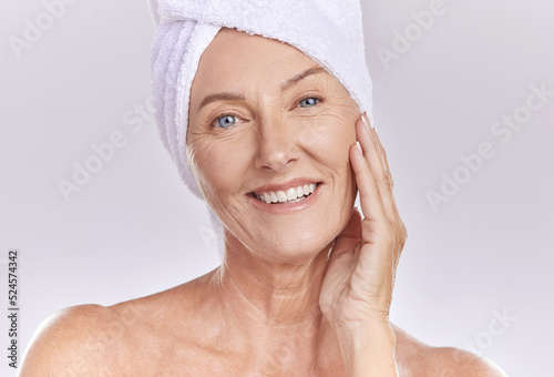 Portrait of happy woman wear a towel on head after enjoying a refreshing shower and healthy skincare. Senior beauty, cosmetic and face model smile while posing against a grey copy space background