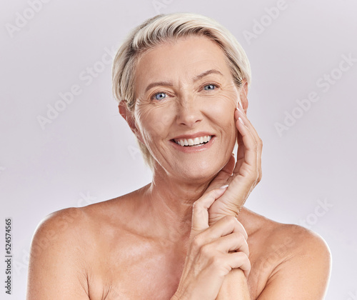 Portrait of happy smiling mature caucasian woman looking positive and cheerful against studio background. Smooth face and skin of an older female or antiaging beauty model doing her skincare routine