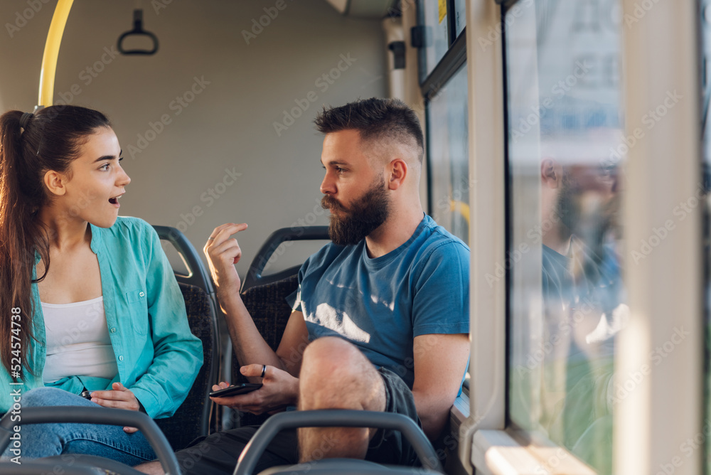 Young couple of friends talking while riding a bus in the city Young couple of friends talking while riding a bus in the city