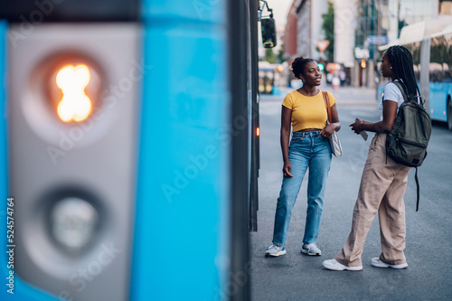 Two african american woman waiting for a public transport at a bus stop