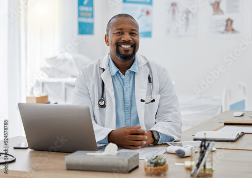 Doctor  medical healthcare worker and male physician at hospital or clinic working with stethoscope and electronics. GP man on laptop reading emails  patient records and documents in covid pandemic