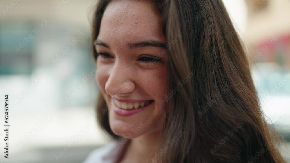 Young hispanic woman smiling confident looking to the side at street
