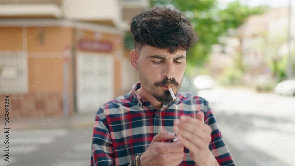 Young hispanic man smoking at street