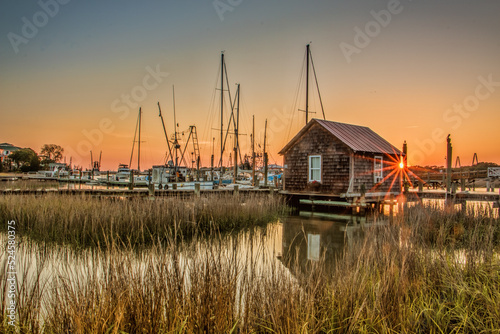sunburst reflection off water at marina with wooden hut