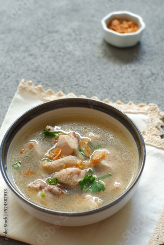 a bowl of chicken soup in grey background