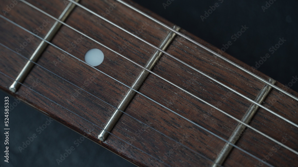 Guitar neck of black electric guitar on dark background