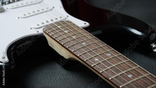 Guitar neck of black electric guitar on dark background