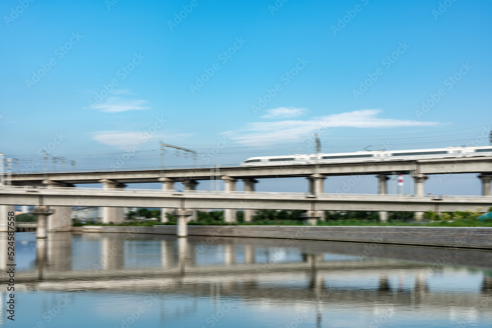 High-speed train passes through railway bridge in modern Chinese city High-speed train passes through railway bridge in modern Chinese city