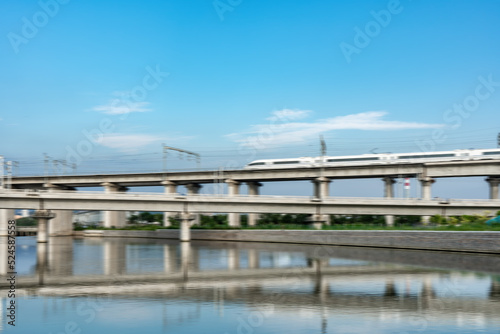 High-speed train passes through railway bridge in modern Chinese city