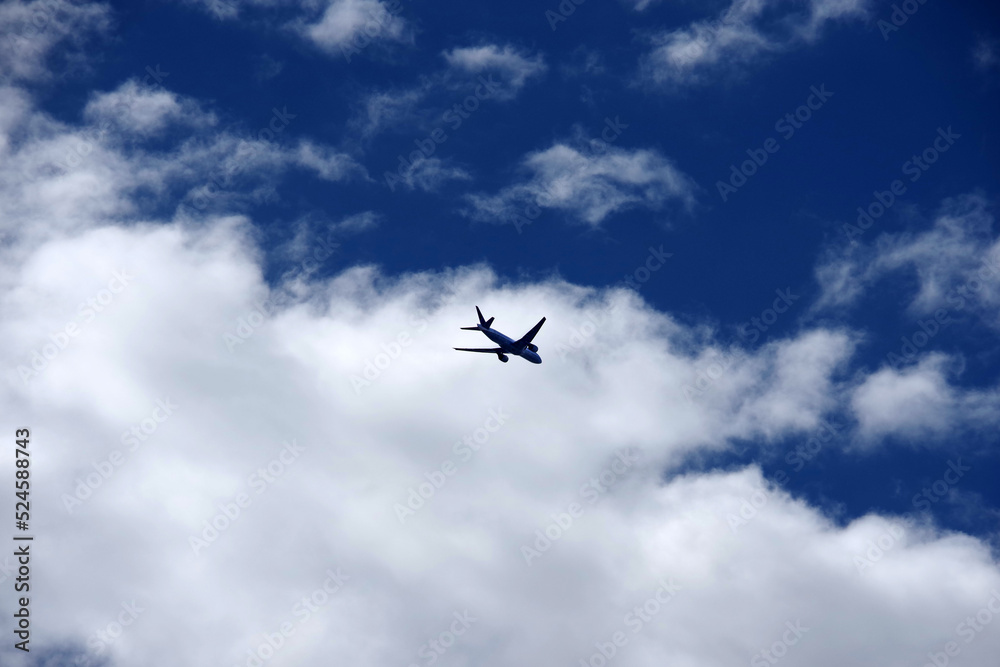 A passenger airplane flying into the clouds and sky