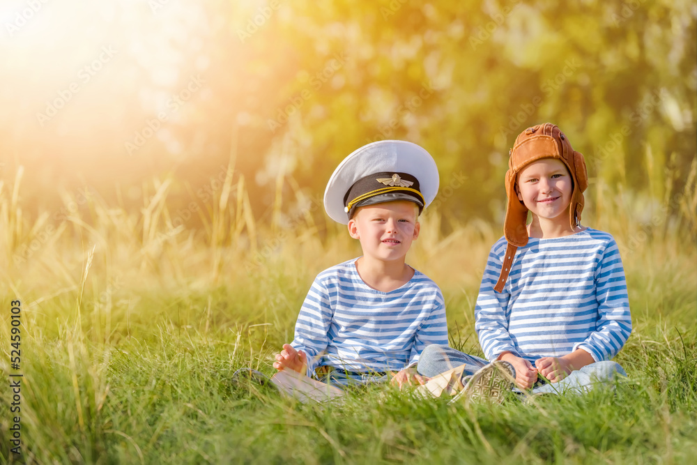 Little boys is playing.
A cheerful and happy children imagines himself as a pilot and captain on a summer day in an open-air field against the backdrop of a forest. Read a book about adventure.