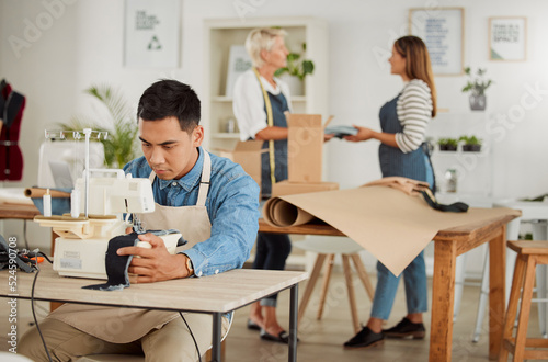 Tailor, seamstress and creative designer working on a sewing machine in a design studio or workshop. Fashion, style and creativity with a young man knitting and stitching while making trendy clothing