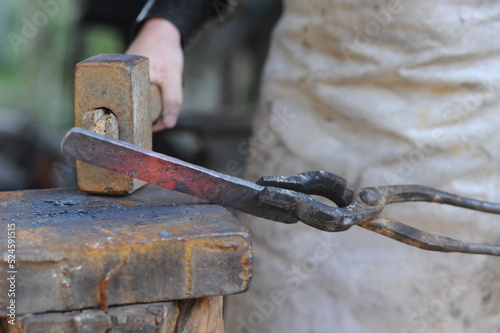 Almaty, Kazakhstan - 09.24.2015 : A blacksmith makes a metal holder for knives and tools in the workshop.