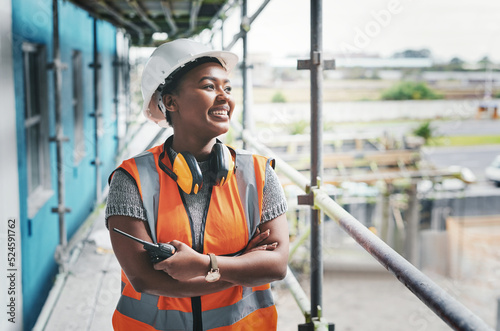 Fototapeta A happy, smiling and cheerful young black woman or senior construction industry worker standing at a building site