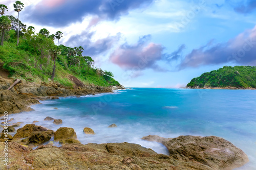 Naiharn Beach in Phuket Thailand, turquoise blue waters, lush green mountains colourful skies. Phuket is a tropical island many palms