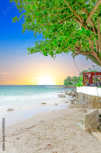 Naiharn Beach in Phuket Thailand  turquoise blue waters  lush green mountains colourful skies. Phuket is a tropical island many palms
