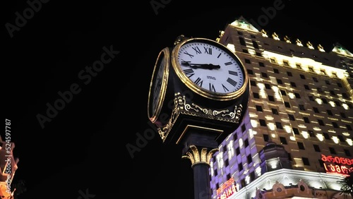 Close-up of old clock on pole on street with building in background. Batumi, Georgia. Europe Square. View of old town at night. Retro style. Clock with Roman chickens. Camera movement. photo